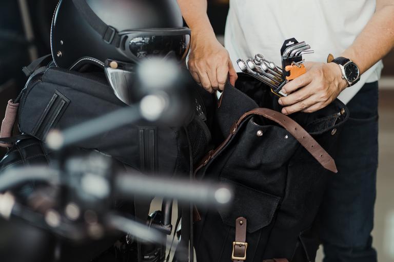 Fahrer bereitet Werkzeug vor und packt es vor der Reise in die Satteltasche oder in die Seitentasche seines Motorrads.