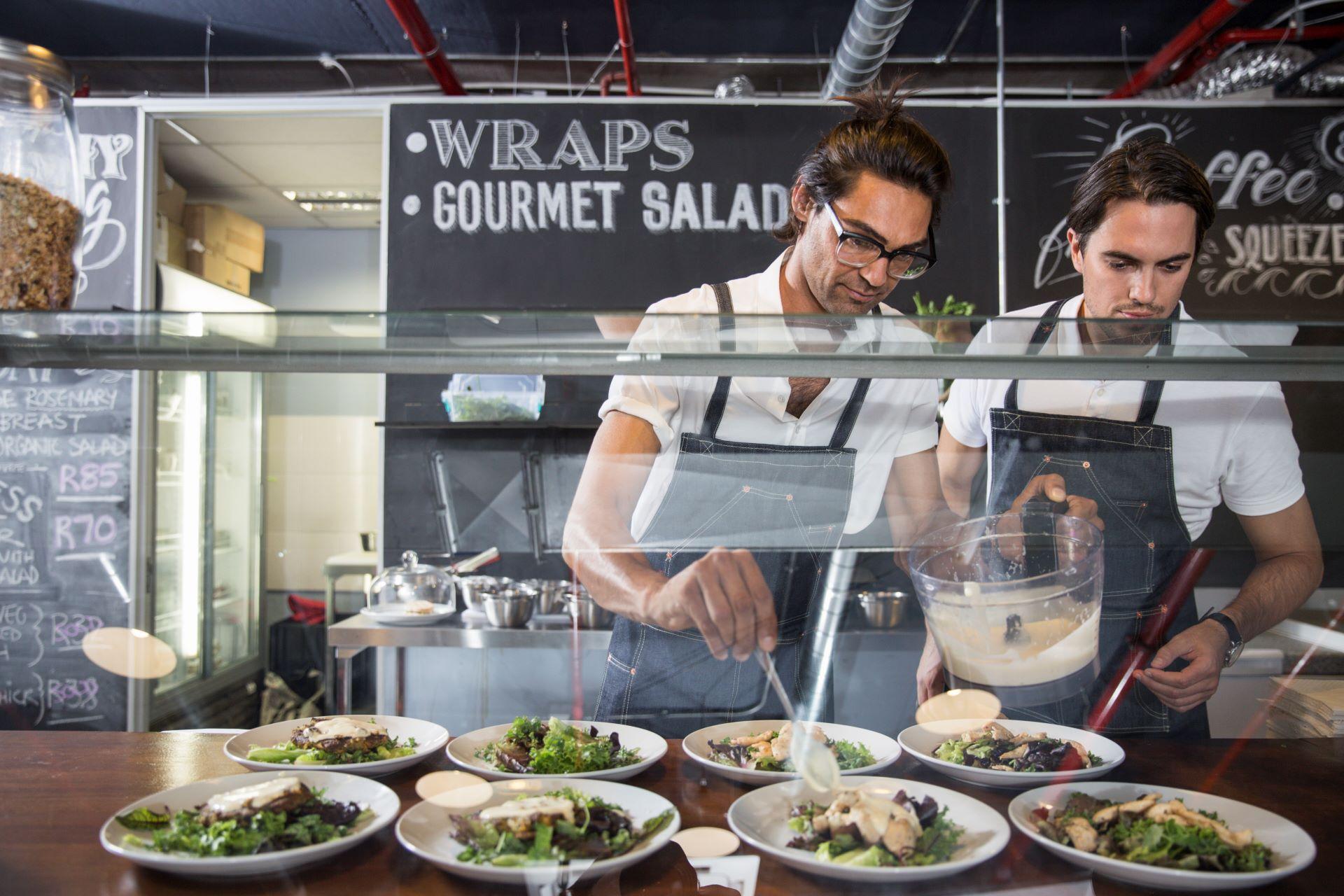 Restaurantmitarbeiter bereiten Salate an Salattheke zu