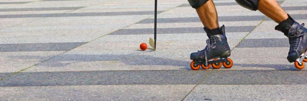 Ein Inlinehockey-Spieler mit Inline-Skates führt den Puck über den Asphalt und zeigt präzise Ballkontrolle.