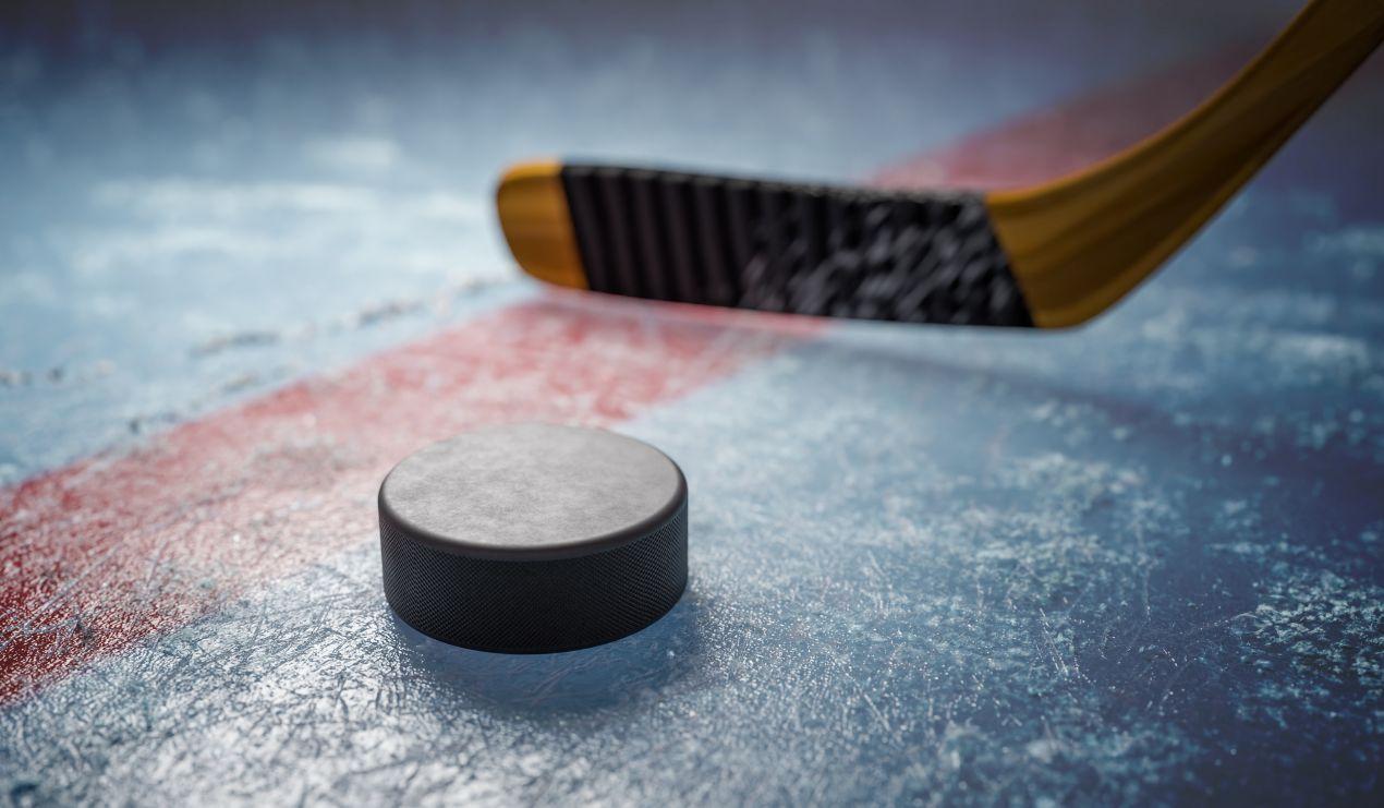 Nahaufnahme eines Hockey-Pucks mit Schläger auf dem Spielfeld – ein zentraler Bestandteil im Inlinehockey und Eishockey.