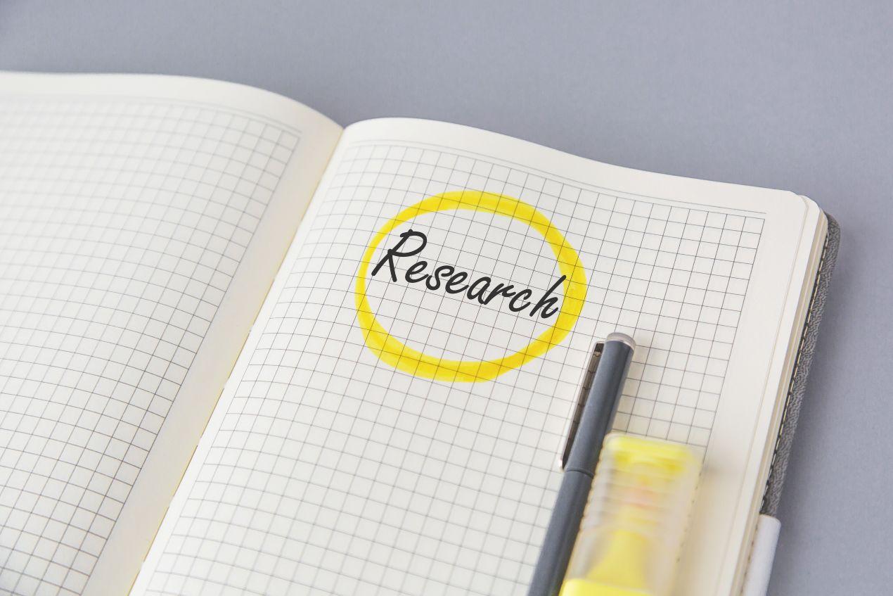 Notizbuch mit gelb markiertem Wort ‚Research‘ – Symbol für Struktur, Planung und wissenschaftliche Sorgfalt beim Doktorarbeit schreiben lassen