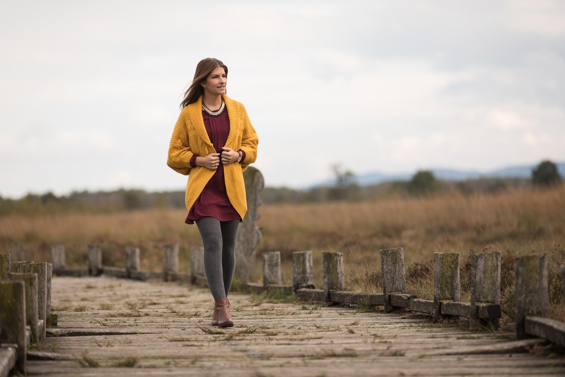 Frau geht entspannt über Holzsteg in herbstlicher Landschaft | Elf Bar Vape